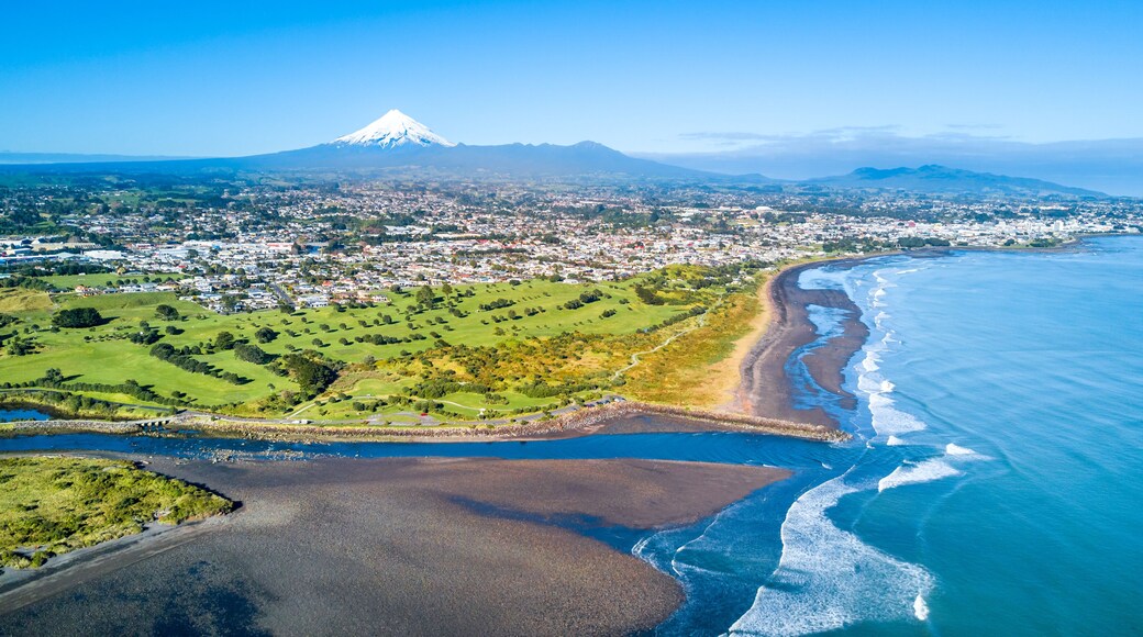 Aerial view on Taranaki coastline with a small river and New Plymouth and Mount Taranaki on the background. Taranaki region, New Zealand