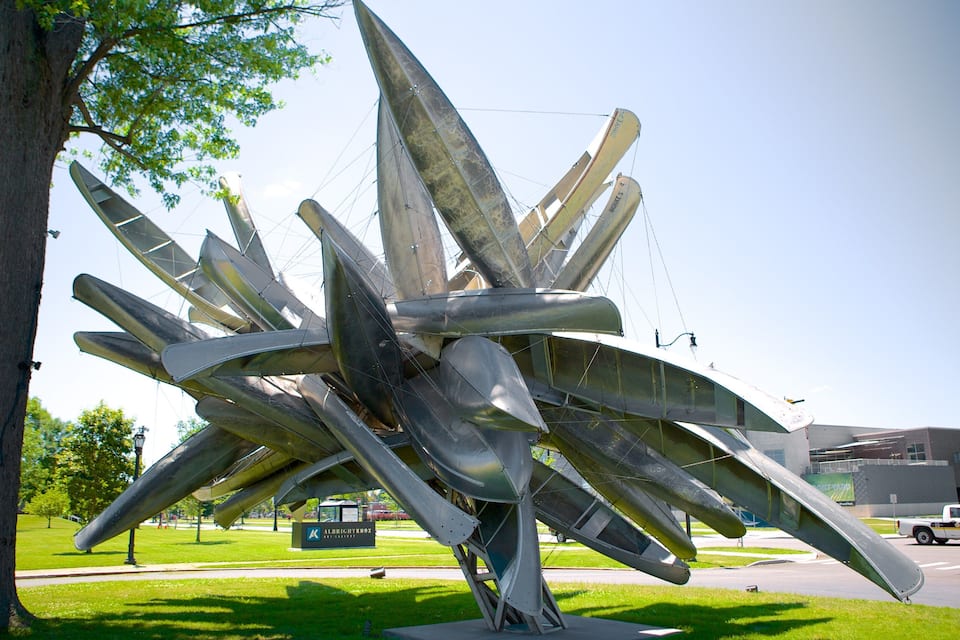 A large metallic sculpture with multiple planes in a park.