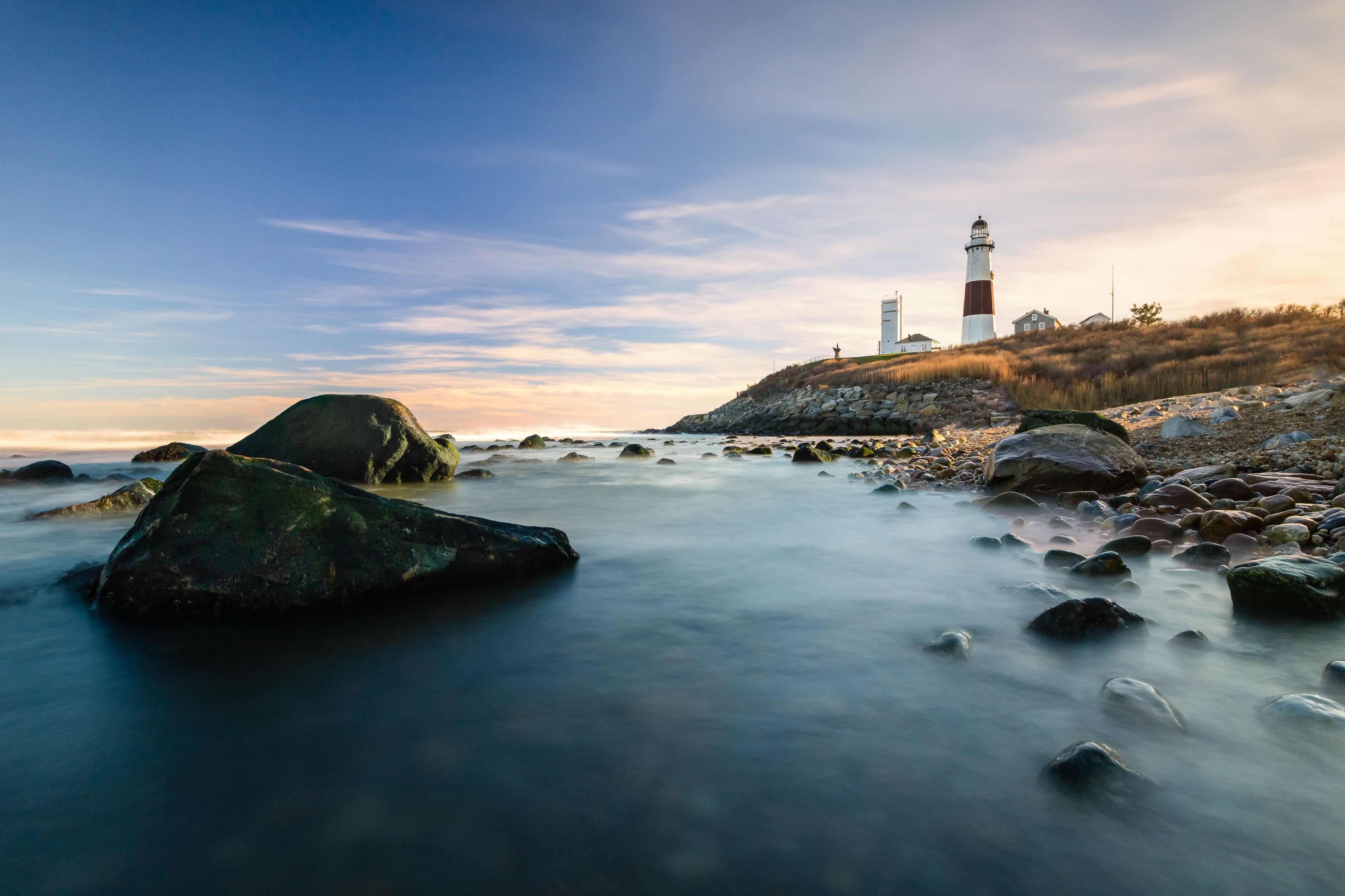 A lighthouse on a rocky shore with a clear sky.