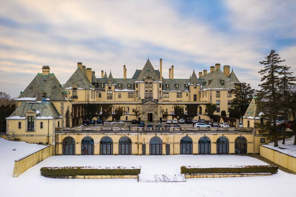 A large, historic building with multiple towers and arched windows, surrounded by snow.