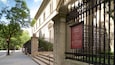 Ein historisches Gebäude mit schmiedeeisernem Zaun und einer Tafel, die die Öffnungszeiten und Eintrittspreise der Frick Collection angibt.