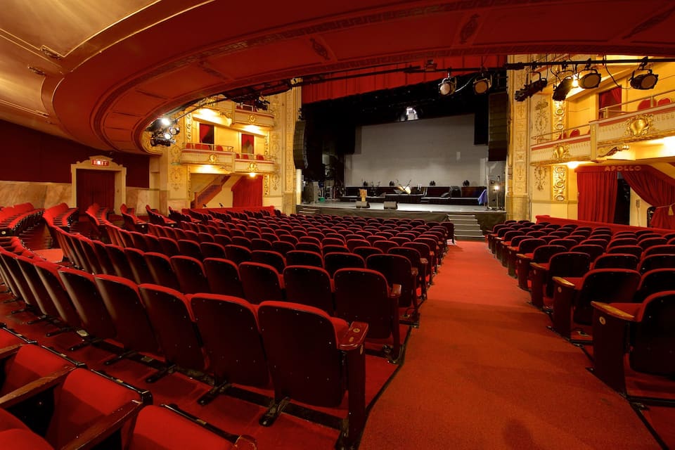 A theater with red seats and a stage.