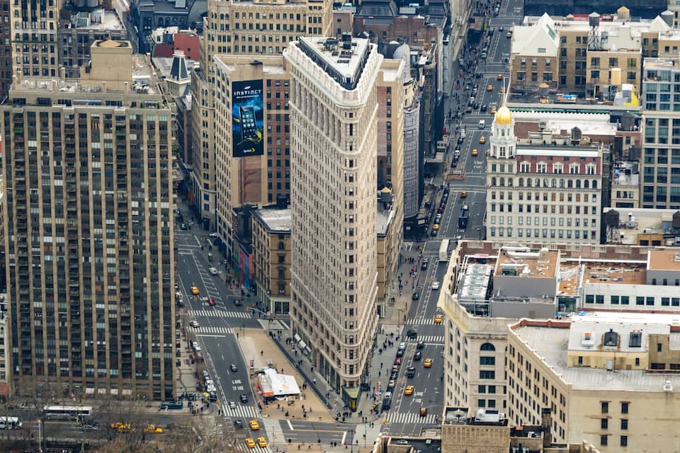 A cityscape with tall buildings, busy streets, and a prominent building with a large advertisement.