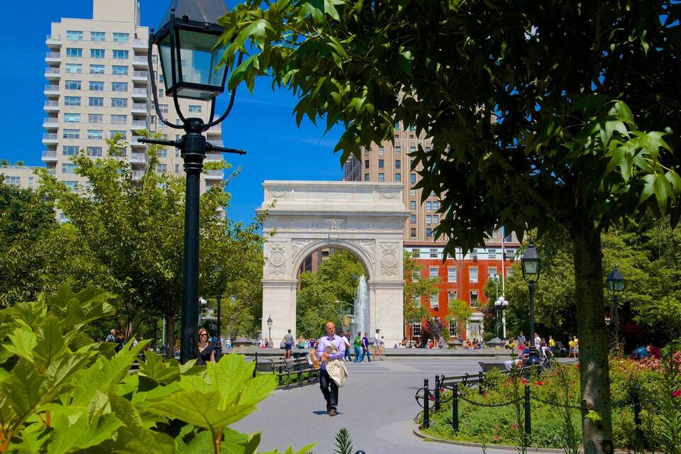 Un parque urbano con un arco, árboles y una fuente.