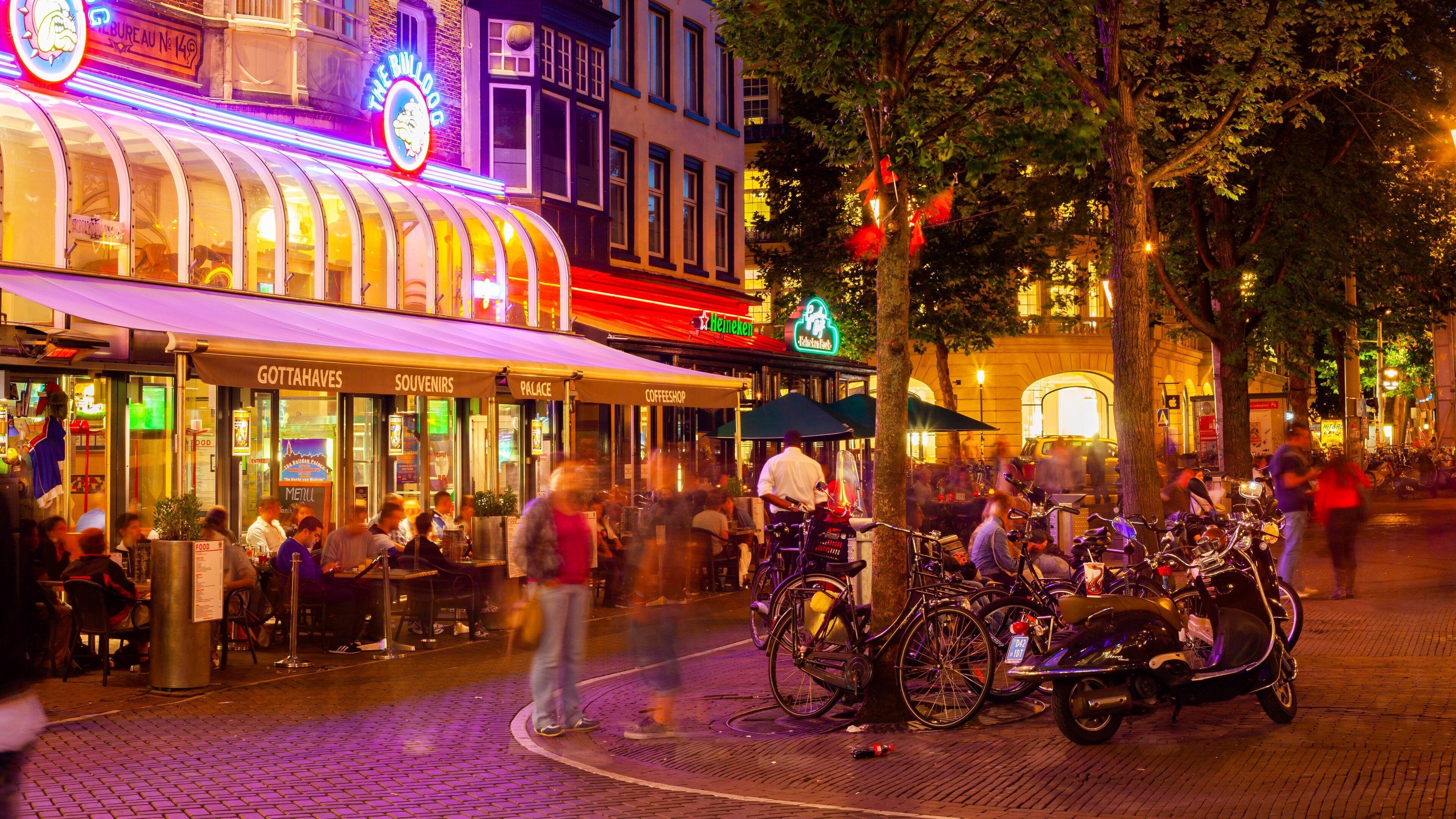 A lively street scene with a variety of shops and cafes, including a Heineken sign and a cafe named 'Palace'.