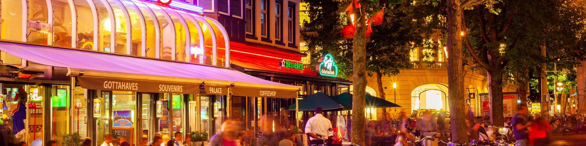 A lively street scene with a variety of shops and cafes, including a Heineken sign and a cafe named 'Palace'.