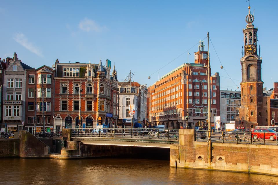 A canal with a bridge, historic buildings, and a clock tower in a European city.
