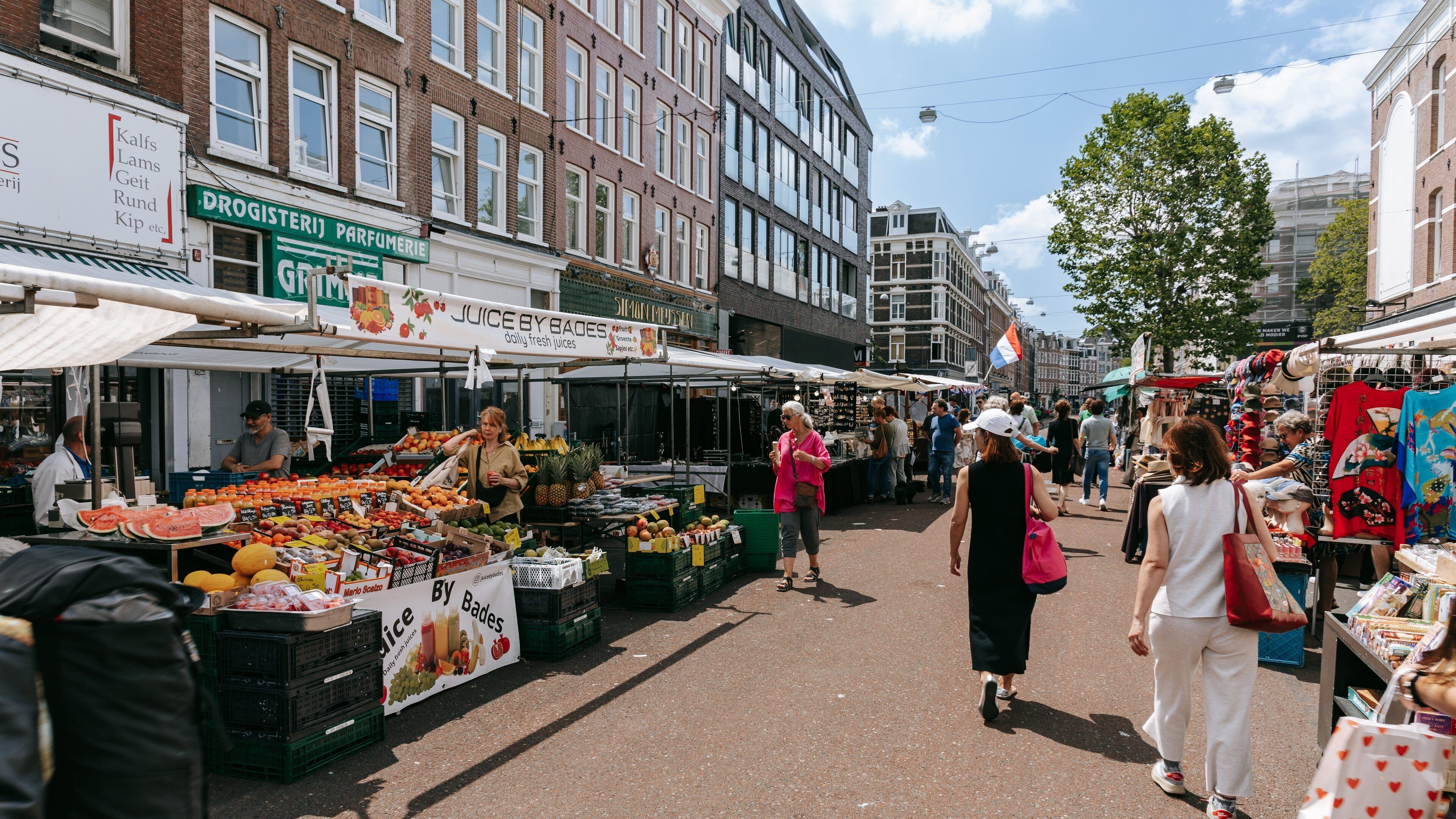 A bustling outdoor market with various stalls selling fruits, vegetables, and other goods.