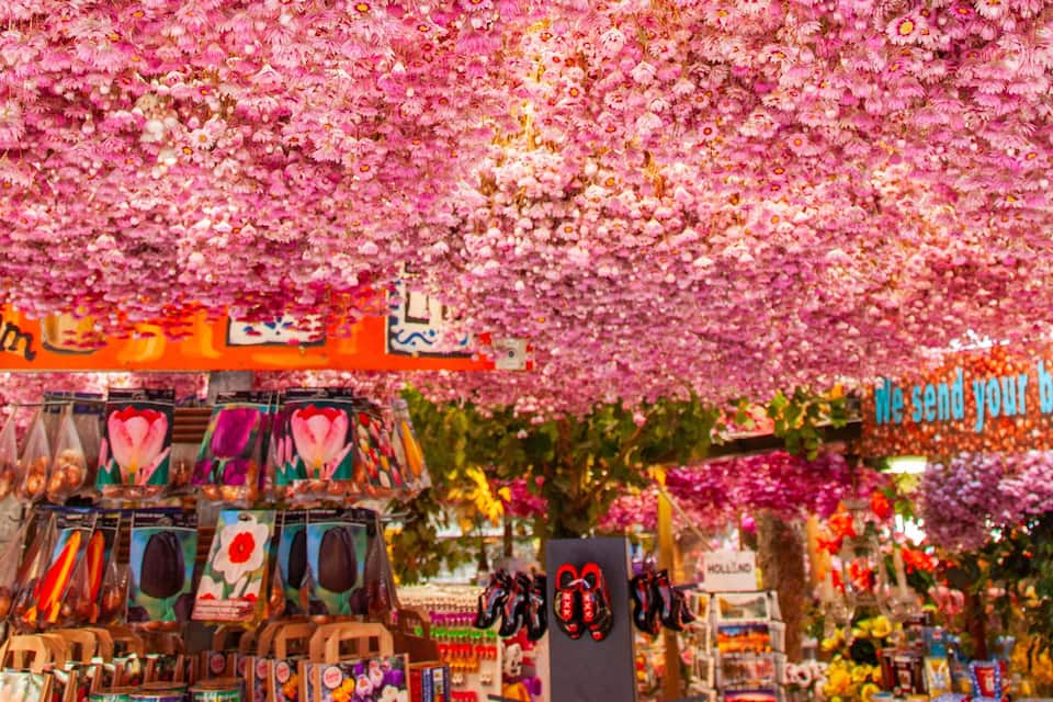 Un étal de marché décoré de fleurs, où sont vendus divers articles.