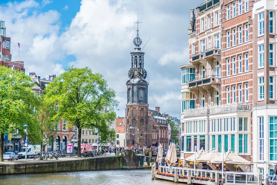 Een historisch uurwerk, een gracht en traditionele Europese architectuur.