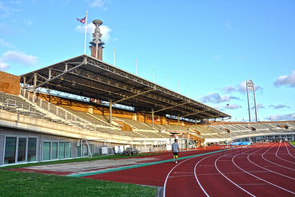 A large stadium with a running track, bleachers, and a flagpole.