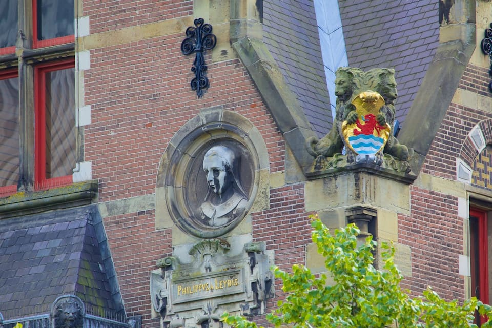 A building facade with a lion statue, a bust, and a plaque reading "PHILIPPVS LEYDIS".