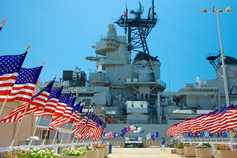 A large naval ship with multiple American flags in the foreground.