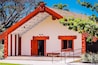Un edificio con fachada roja y blanca, una escalera de madera y un letrero que dice 'Kupe'.