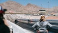 A desert racing track with a digital timer and a 'PENNZOIL' sign.