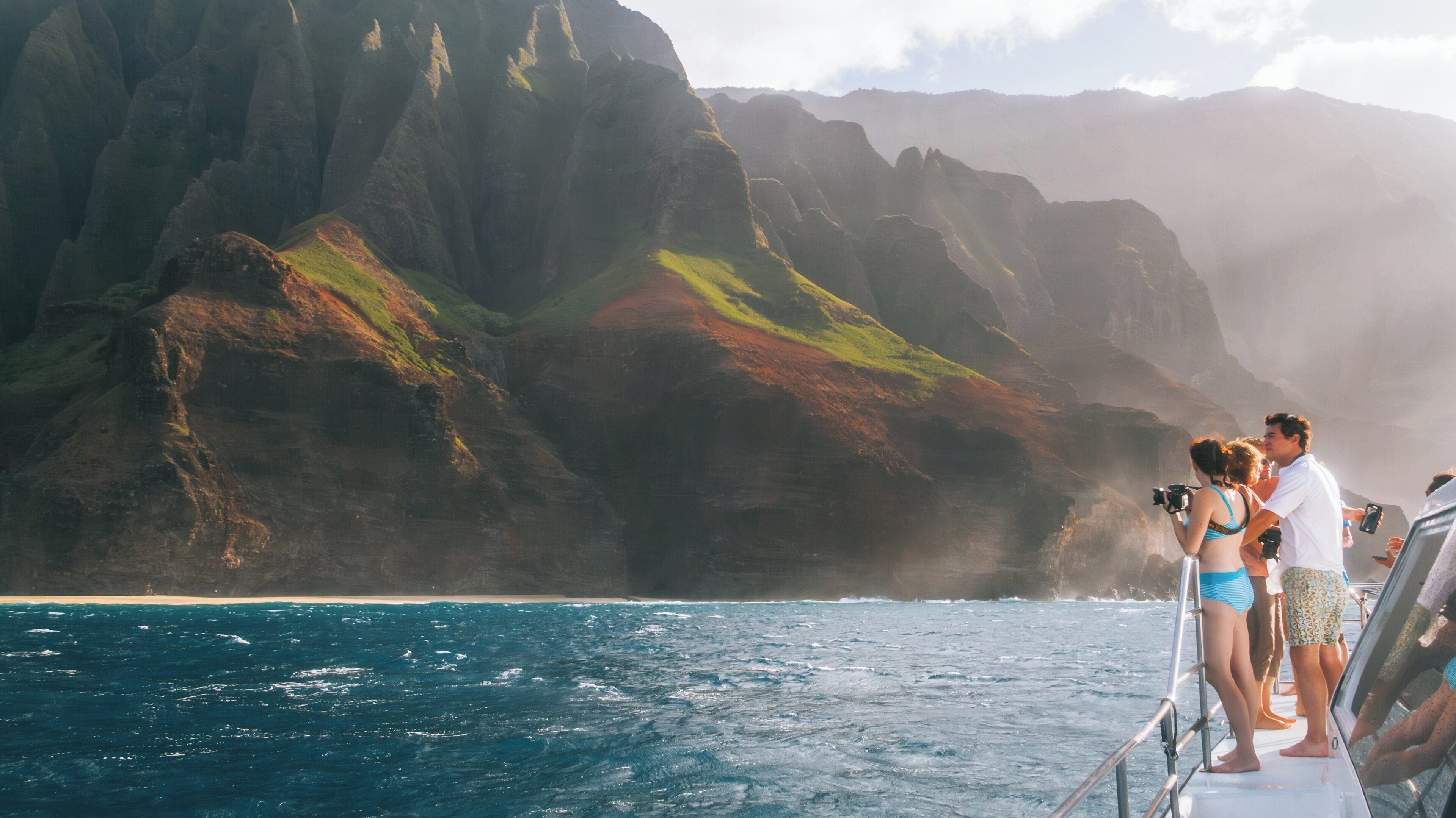 Explorers enjoying breathtaking views of Na Pali Coast in Hanalei, Hawaii while on a boat tour amid stunning cliffs and ocean waves