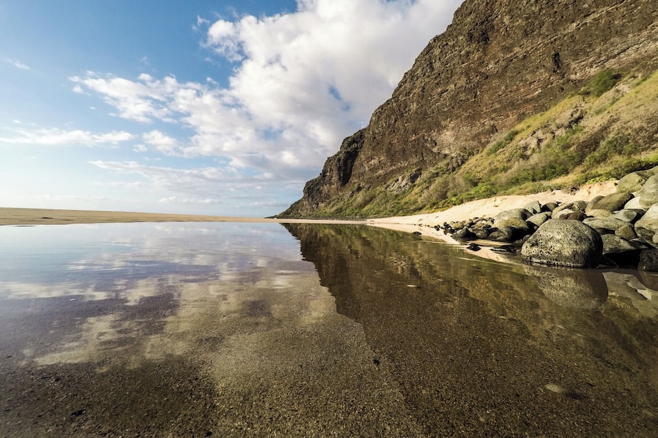 A calm lake with a rocky shoreline and a steep cliff.