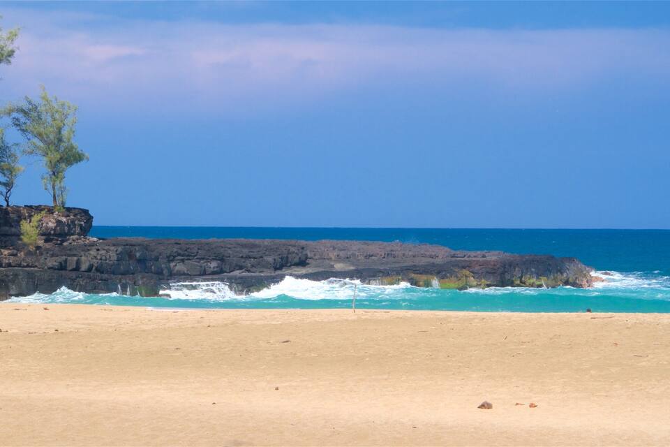 Una platja amb aigües turqueses cristal·lines, roques i vegetació escassa.