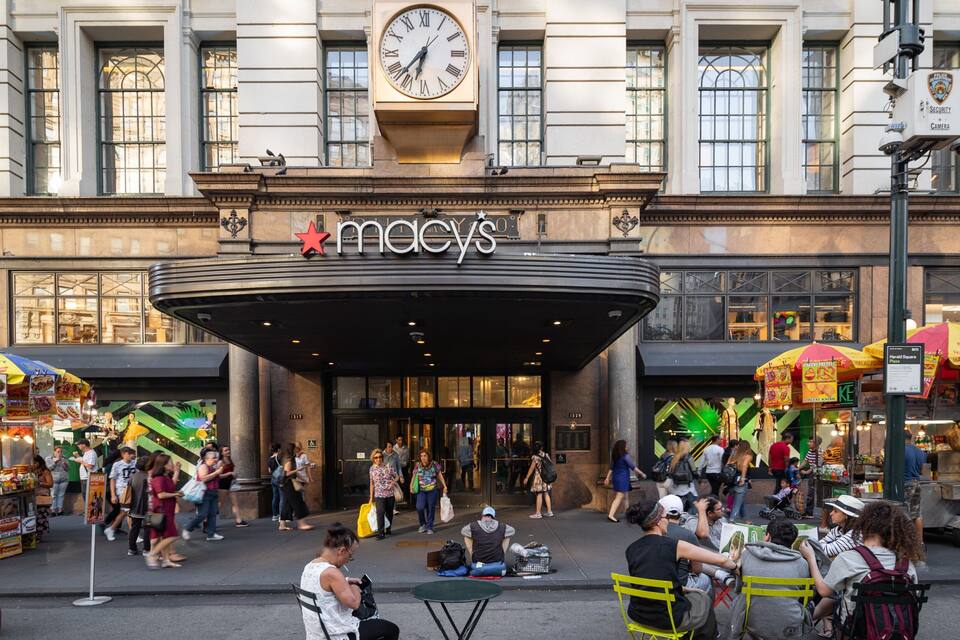 En livlig gatuscen framför varuhuset Macy's, med folk som promenerar och gatuförsäljare.