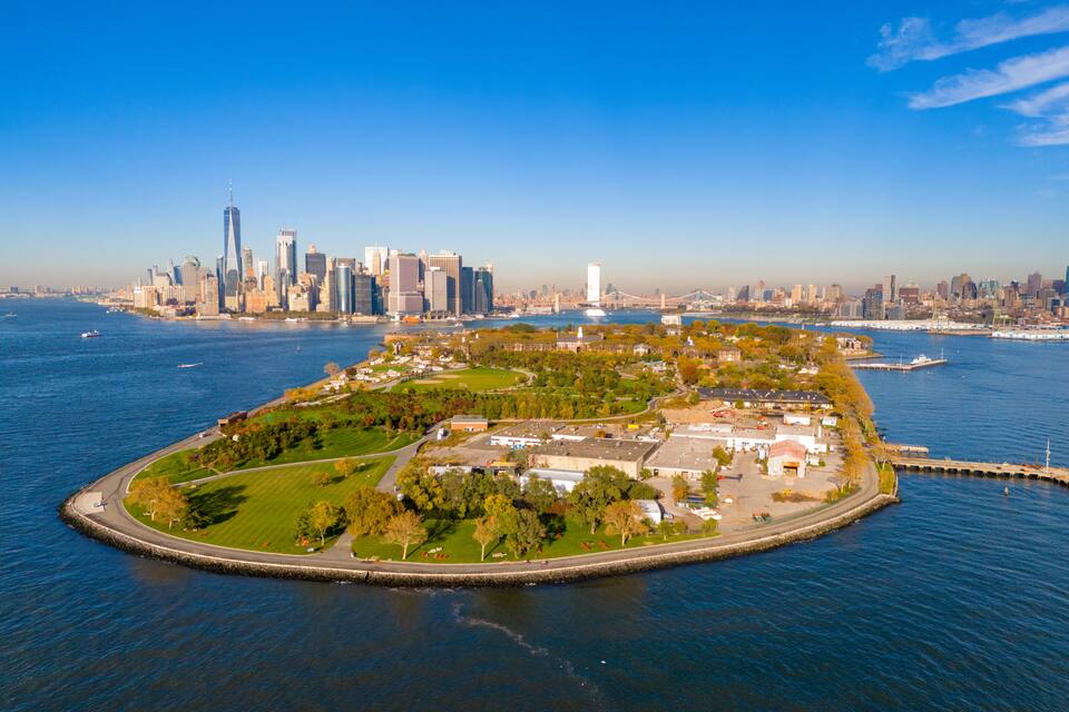 Ein Park am Wasser mit einer Stadtansicht im Hintergrund.