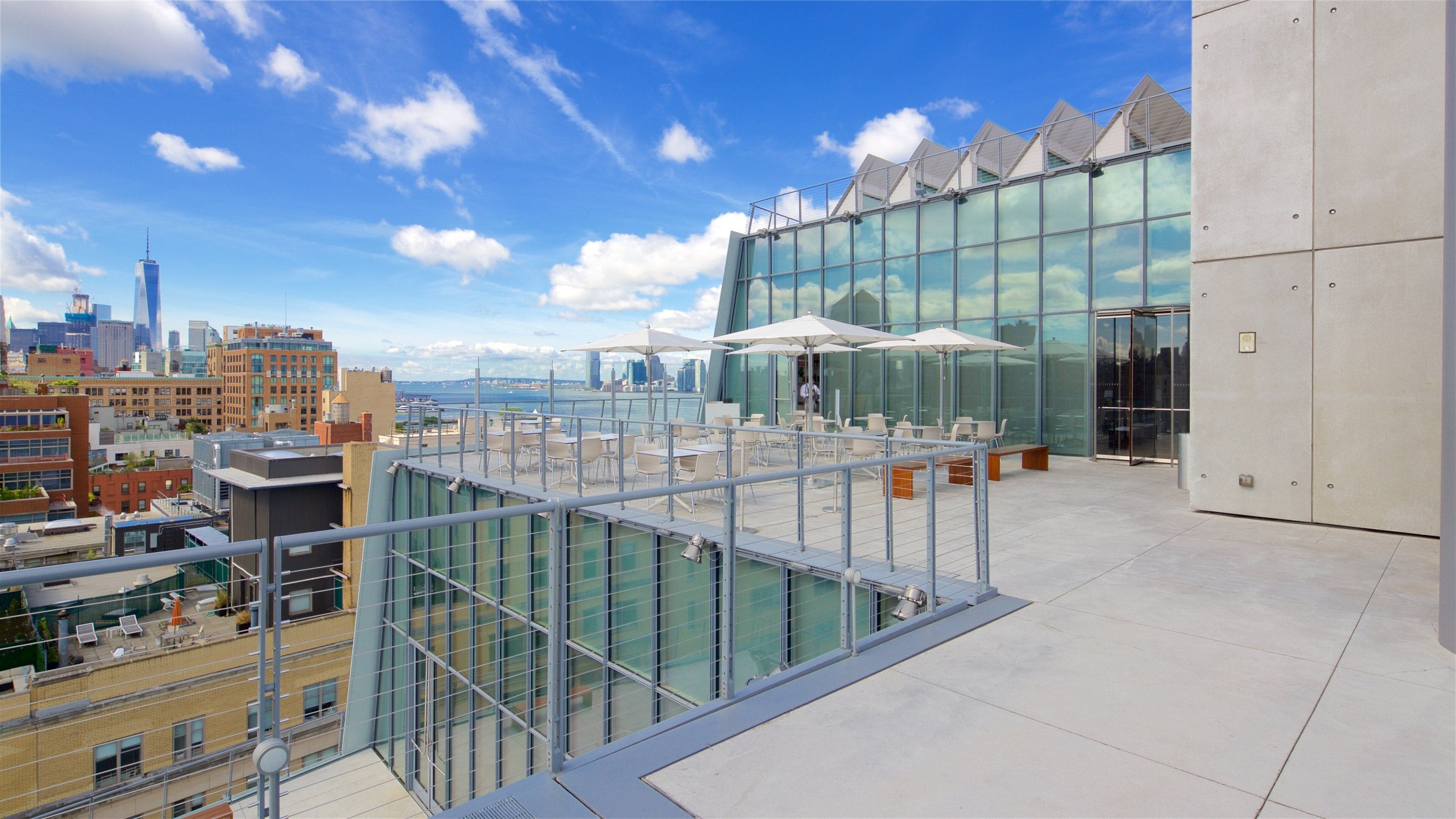 Terraço no telhado com área de estar ao ar livre, vista para um horizonte urbano e um corpo de água.