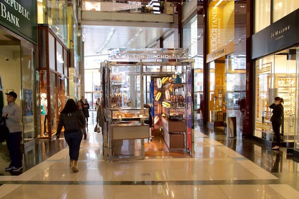 Corredor de um shopping com lojas como Republic Bank e L'OCCITANE.