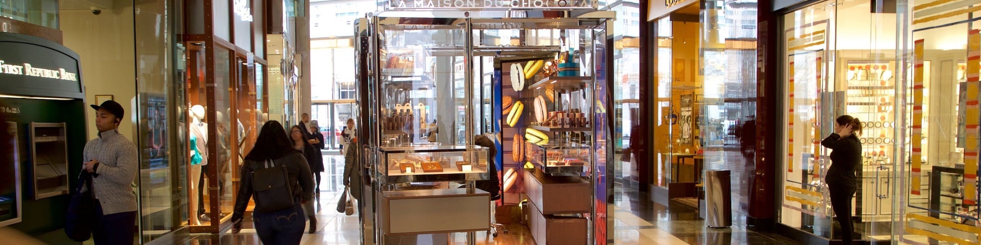 Corredor de um shopping com lojas como Republic Bank e L'OCCITANE.