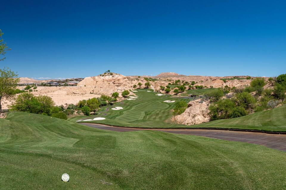 A golf course with a clear view of the surrounding hills and sparse vegetation.