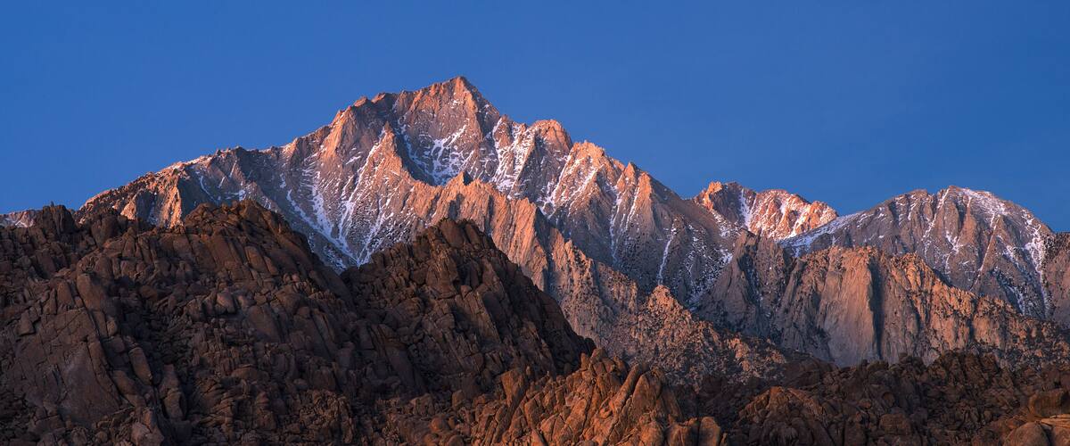 A rugged mountain range with sharp peaks and snow patches.