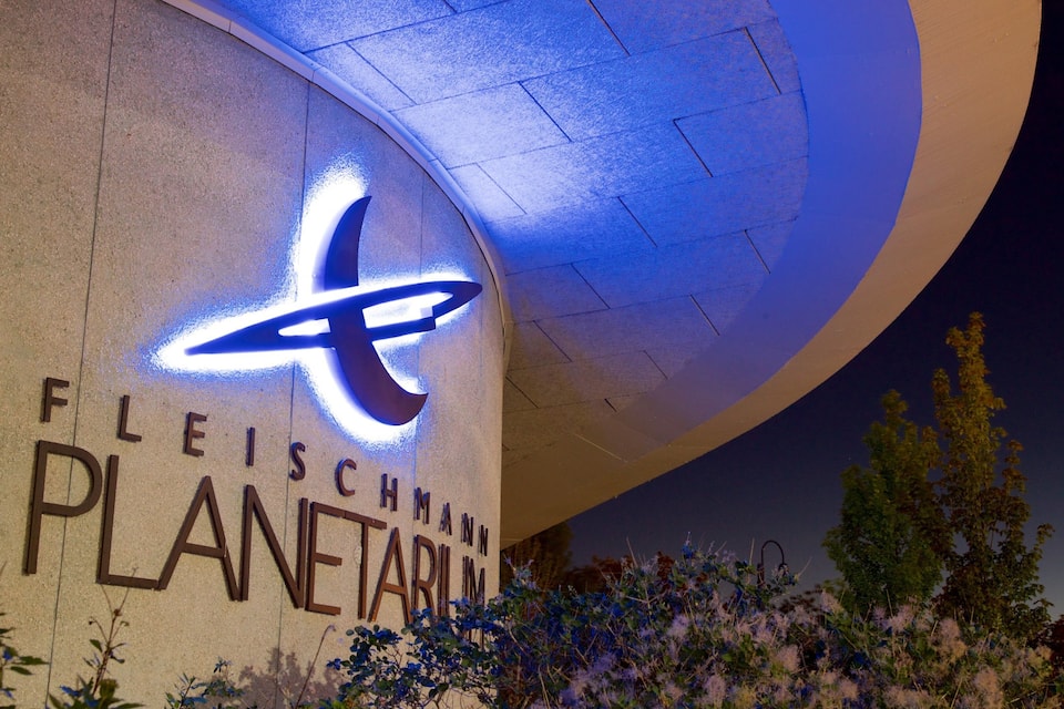 Ein Gebäude mit einem großen, beleuchteten 'x'-Logo und der Aufschrift 'FLEISCHMANN PLANETARIUM' an der Fassade.