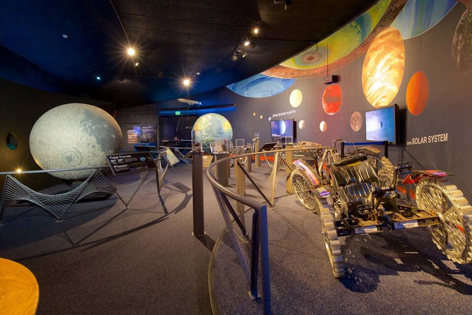 A space exhibit with planetary models, a space shuttle, and a Mars rover.