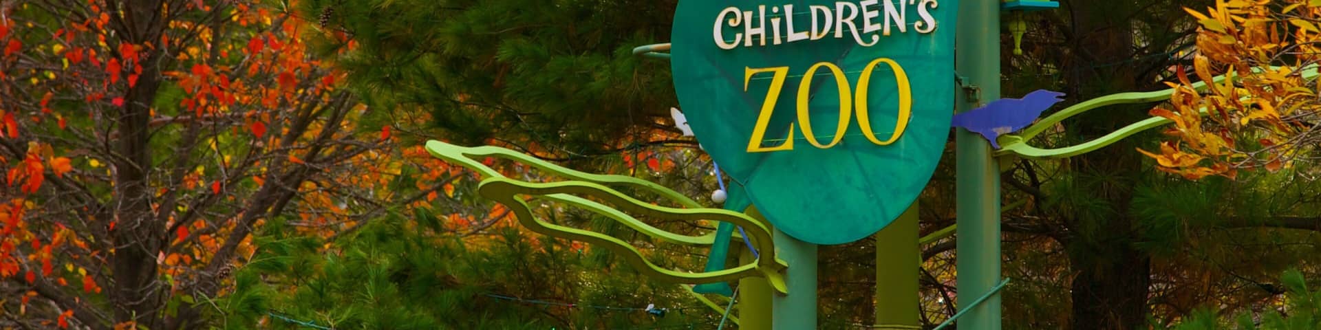 A sign for the Pritzker Family Children's Zoo surrounded by autumn foliage.