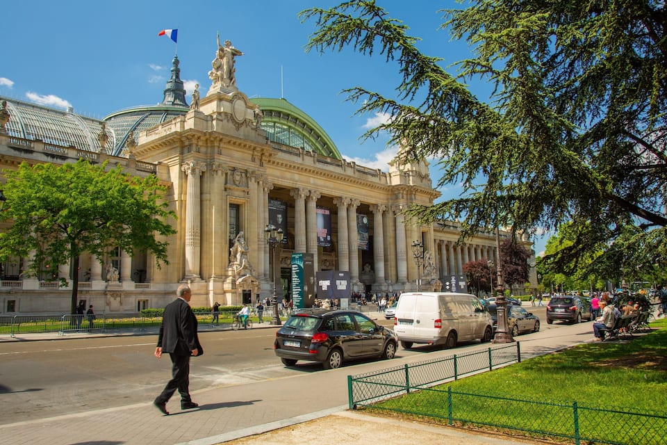 A grand building with classical architecture, a green dome, and a statue on top.