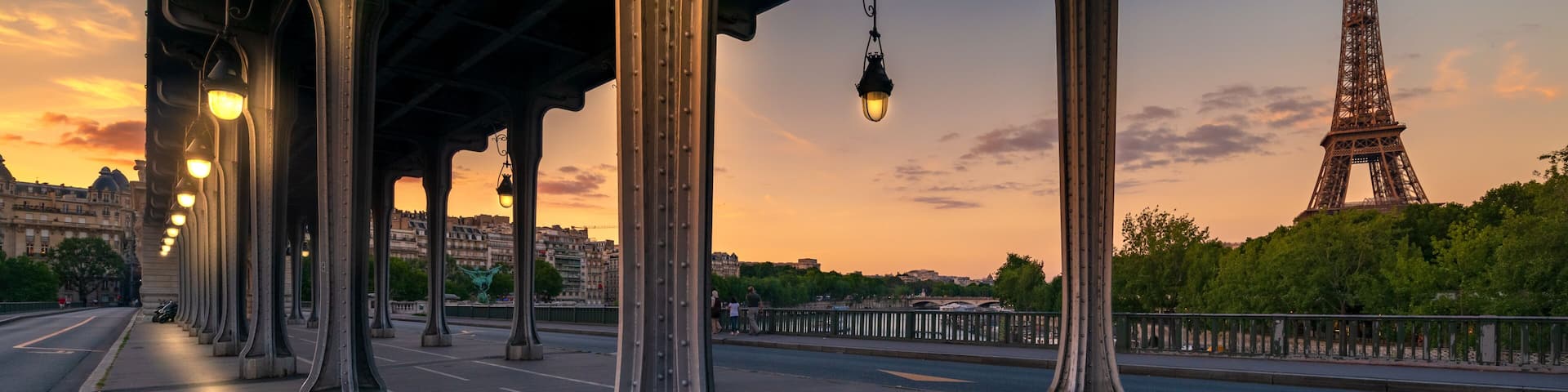Un puente con farolas, un carril bici verde y la Torre Eiffel al fondo.
