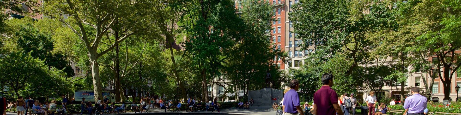 A public square with a fountain, surrounded by trees and buildings.