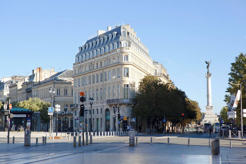 A historic building with ornate architecture, a statue, and a clear blue sky.