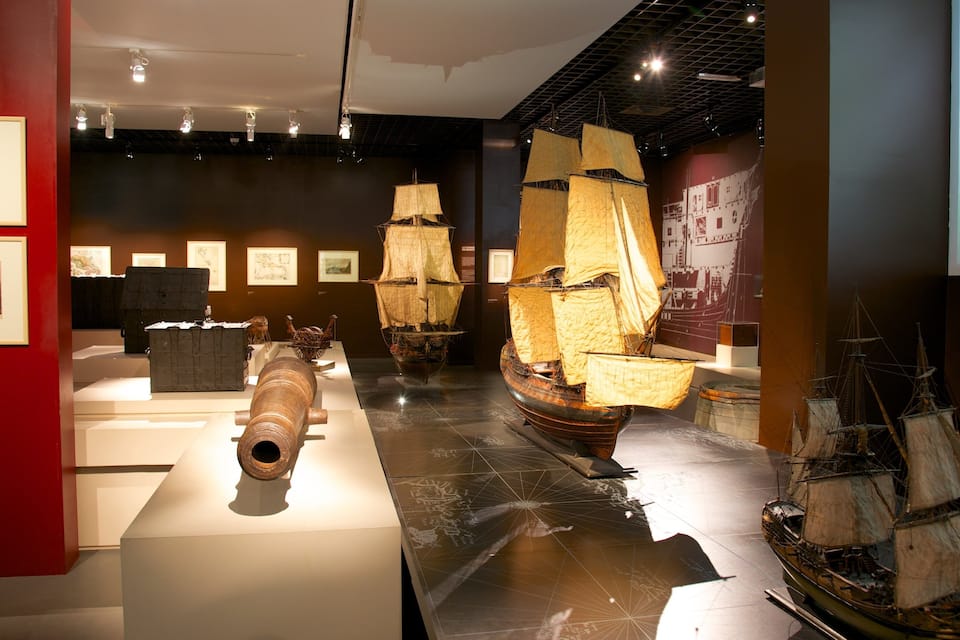A museum exhibit with historical ships and maritime artifacts.