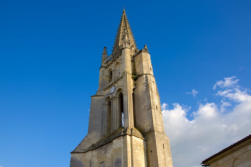 Uma torre de igreja alta com um pináculo pontiagudo contra um céu azul límpido.