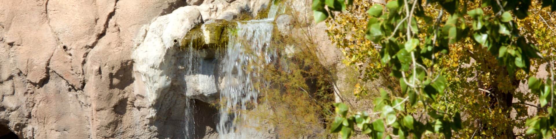 A waterfall cascading down a rocky cliff surrounded by greenery.