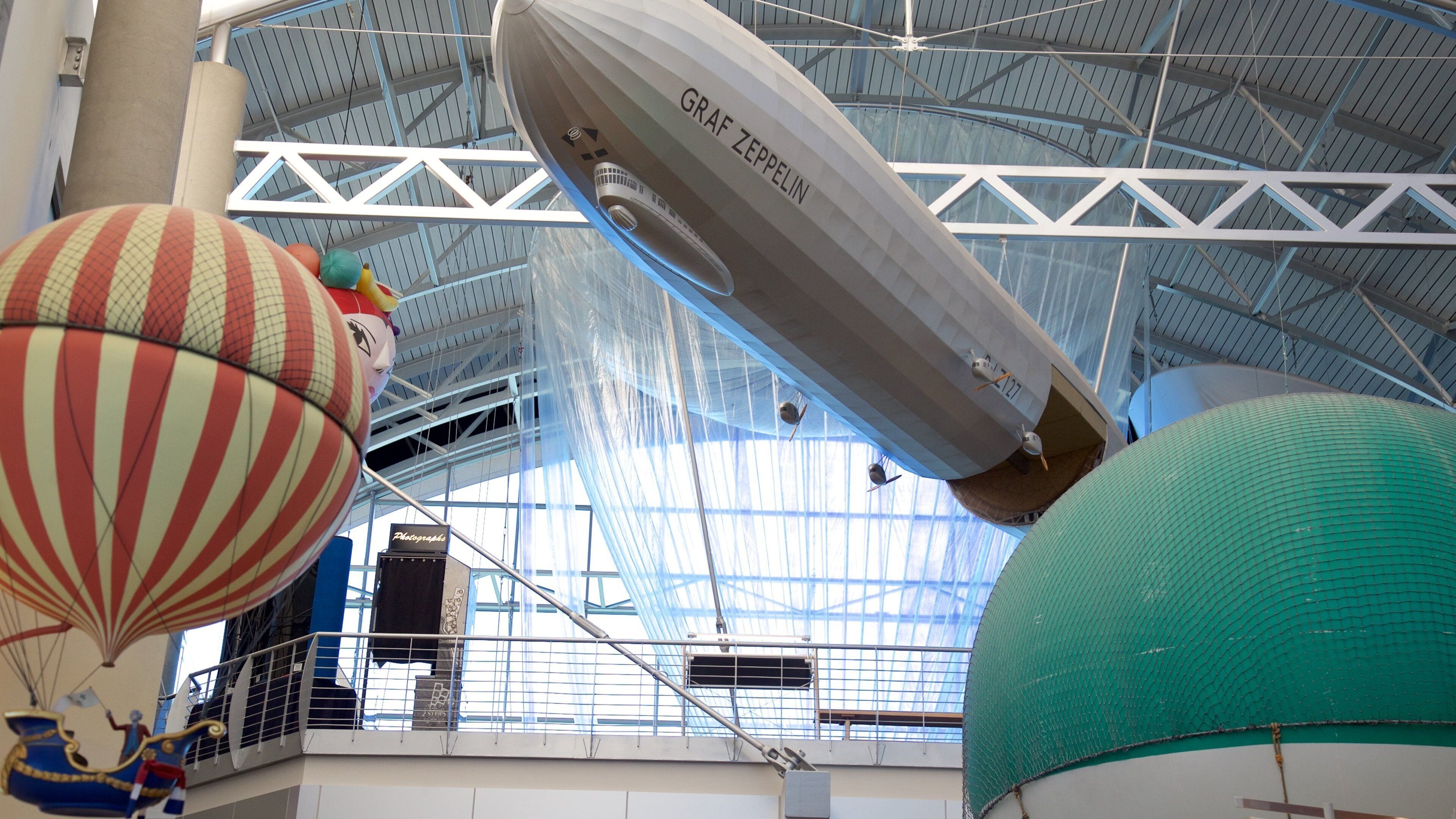 A large indoor exhibition with a zeppelin and hot air balloons.