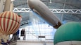 A large indoor exhibition with a zeppelin and hot air balloons.