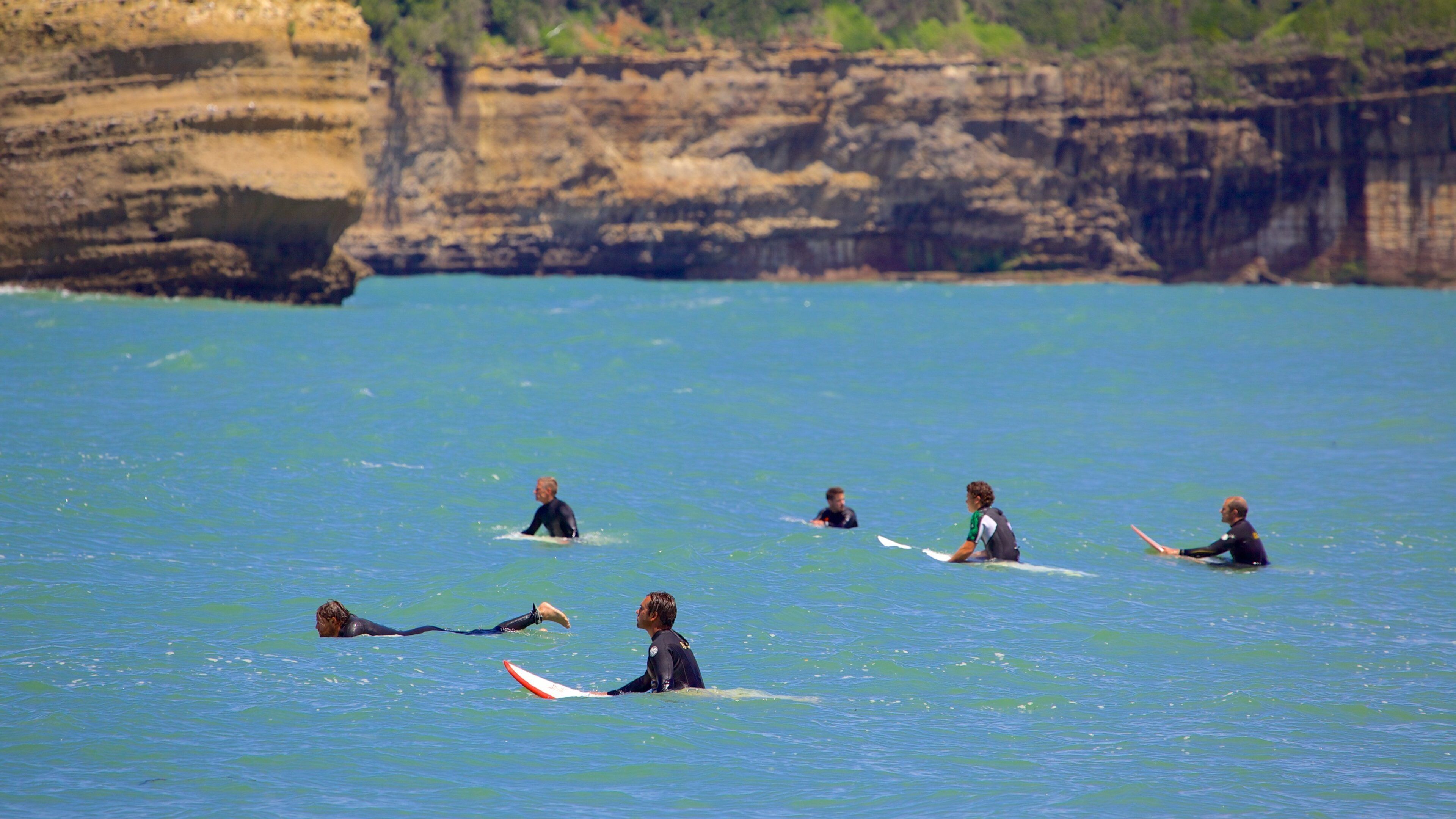 Grande Plage mostrando surfe e litoral acidentado assim como um pequeno grupo de pessoas