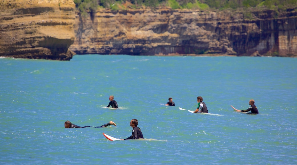 Grande Plage mostrando surfe e litoral acidentado assim como um pequeno grupo de pessoas