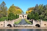 A stone bridge with a water feature and a view of trees in the background.