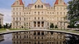 New York State Capitol Building featuring a pond and heritage architecture