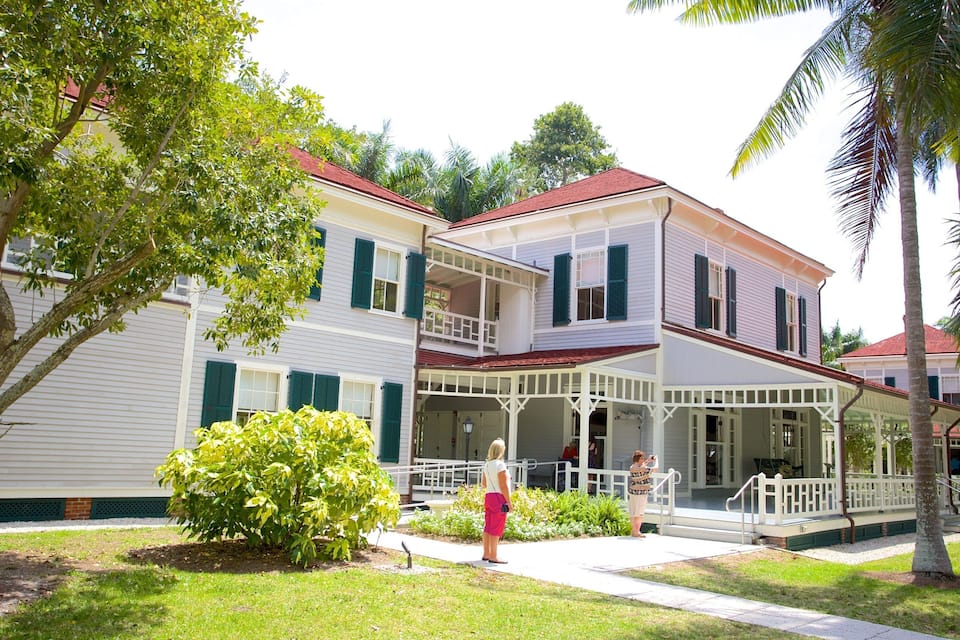 A two-story house with a porch, green shutters, and a red roof.