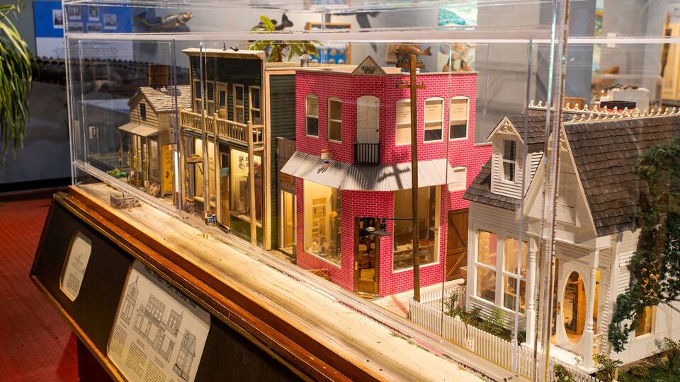 A detailed model of a red brick building with a white picket fence, a small porch, and a street lamp.