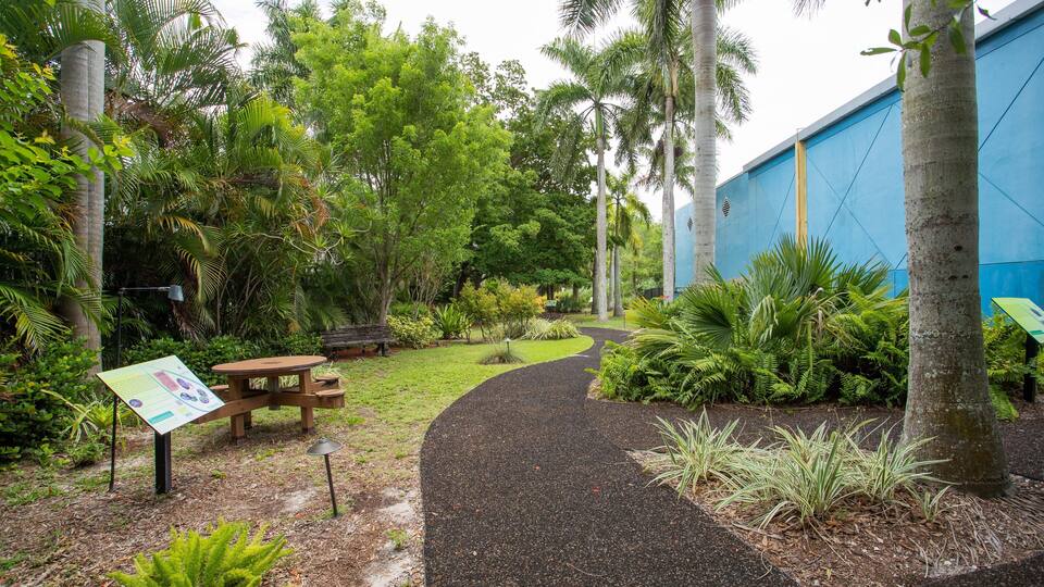 A garden with a curved path, benches, and a signboard.