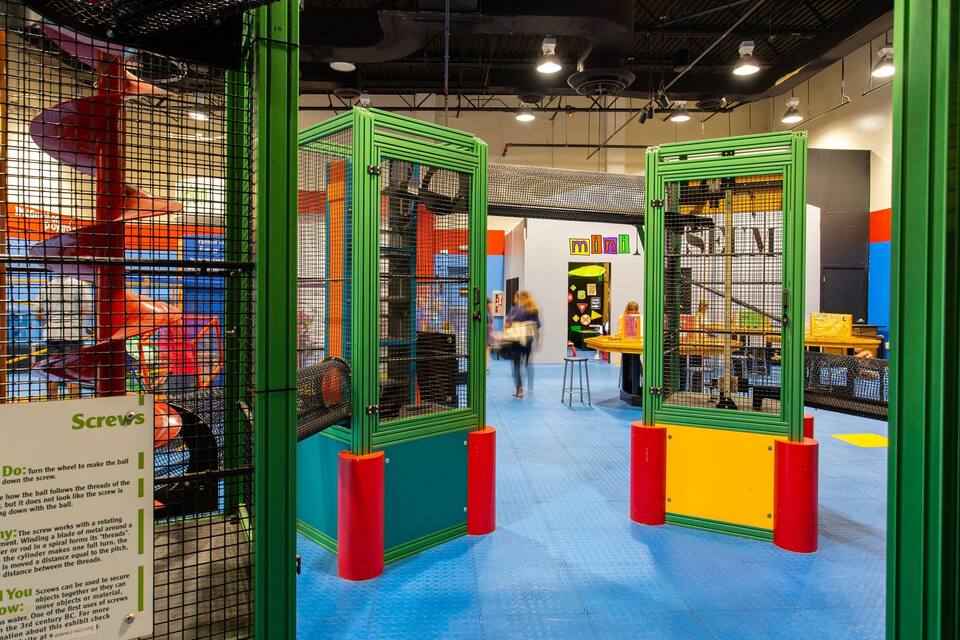 A children's play area with colorful play structures and educational exhibits.