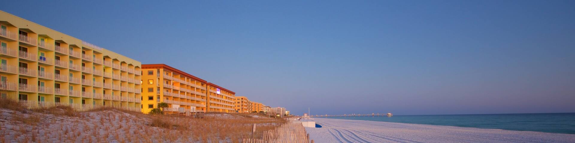 A snow-covered beach with a wooden fence and a hotel in the background.